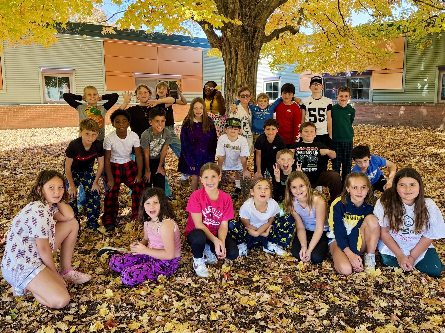 The class gathered beneath a tree with golden autumn leaves.